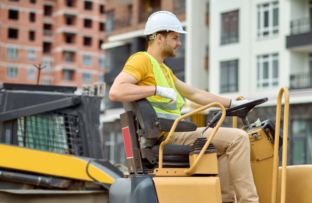 Asphalt Services in Quebec and Montreal with an excavator operator managing heavy machinery on a construction site, preparing the ground for roadwork and paving projects.