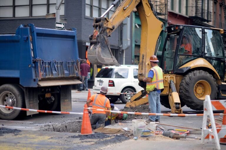 Electrical and plumbing entrances services in Quebec showing a construction site where workers and heavy machinery are preparing underground utility connections for electrical and plumbing installations.