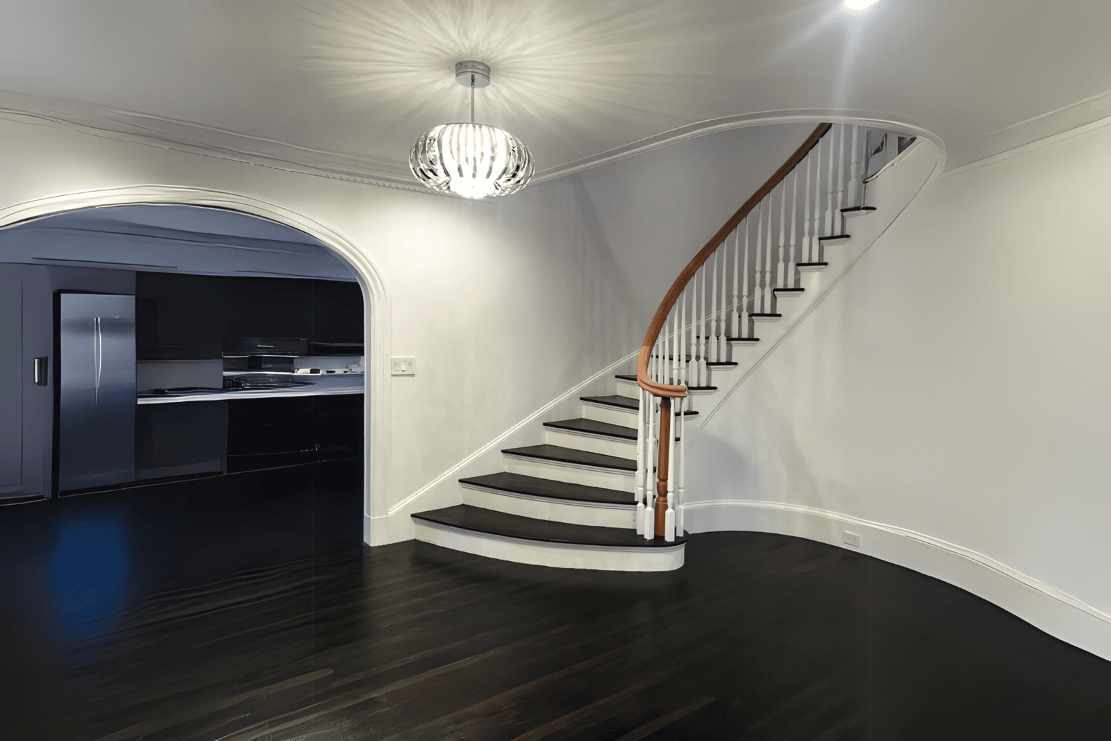 Curved staircase in a Quebec home with dark wood steps and a white railing, showing detailed interior painting and finishing work.