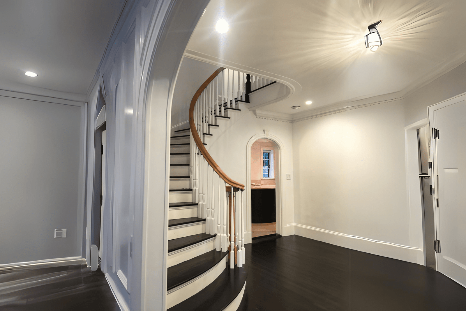curved freestanding staircase with white risers, wooden treads, and a light gray accent wall freshly painted as part of interior painting services in Quebec and Montreal.