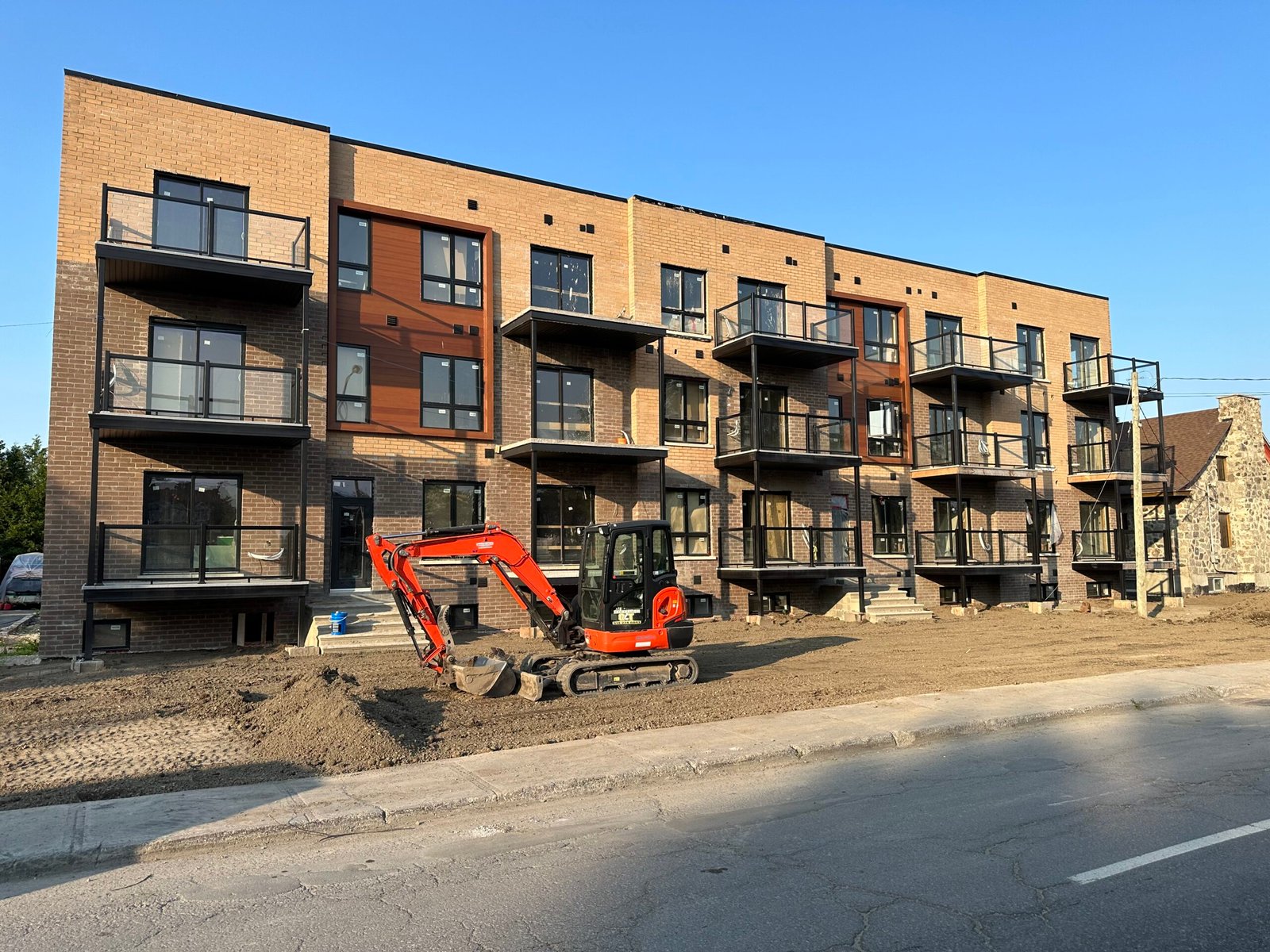 New Construction Quebec and Montreal showing a residential building under construction with an excavator positioned in front of the site.